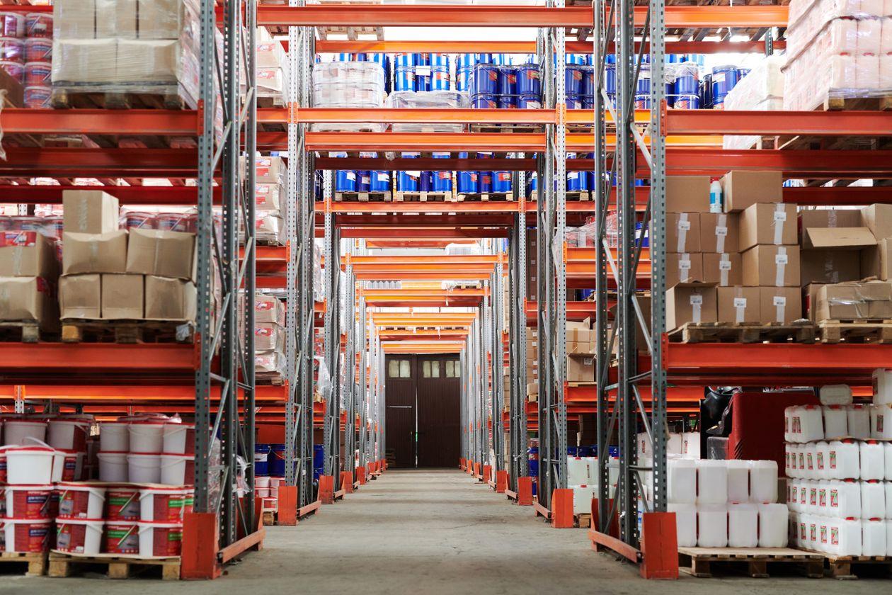 Organized warehouse aisle with boxes, barrels, and pallets on industrial racking
